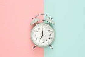 Image for a descriptive exercise using TO BE verb, numbers and adjectives. Alarmclock with a pink and blue background, showing it's 7 o'clock.